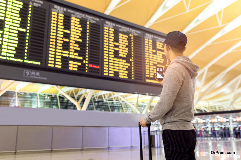 Passenger-looking-at-flights-information-board-in-airport-terminal