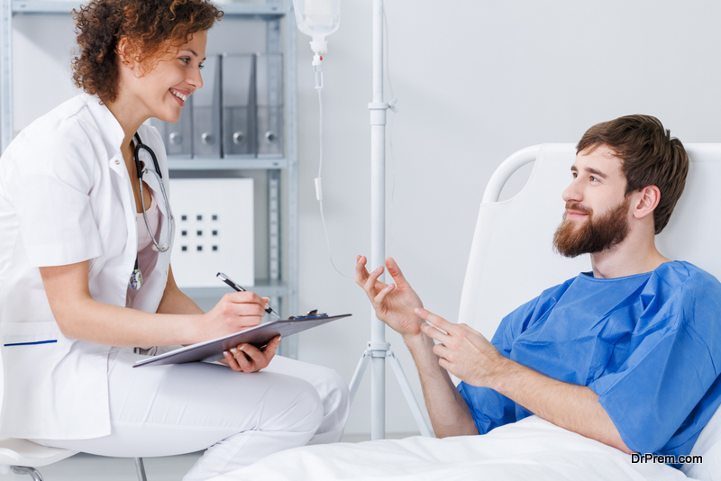 Patient lying in hospital bed on drip talking with friendly nurse