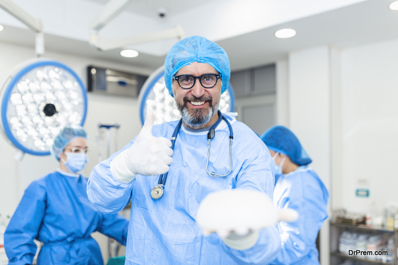 Plastic, Cosmetic Surgeon holding silicone breast implant and showing thumb up