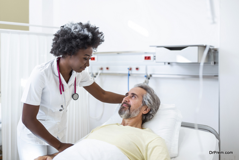 Senior patient on bed talking to African American female doctor in hospital room