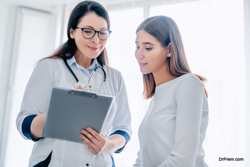 Smiling adult female doctor reporting medical results to young girl patient