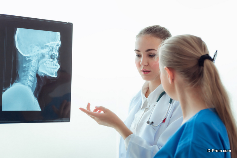 female doctor is examining X-Ray film for her patient in examination room., Healthcare and occupational concept.