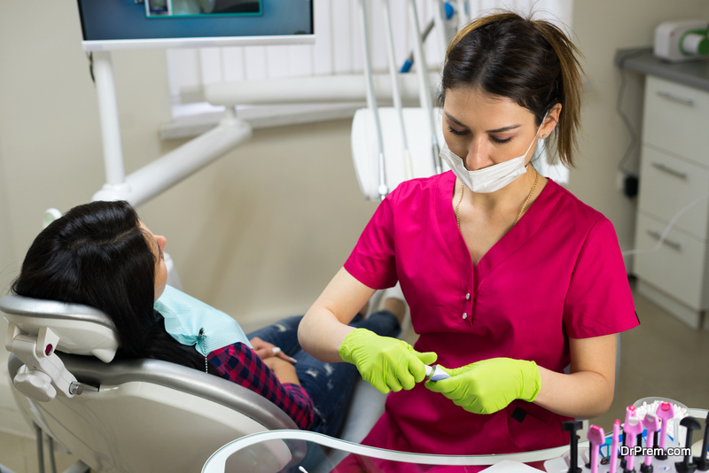 Female dentist at work preparing instruments for examining woman's teeth 