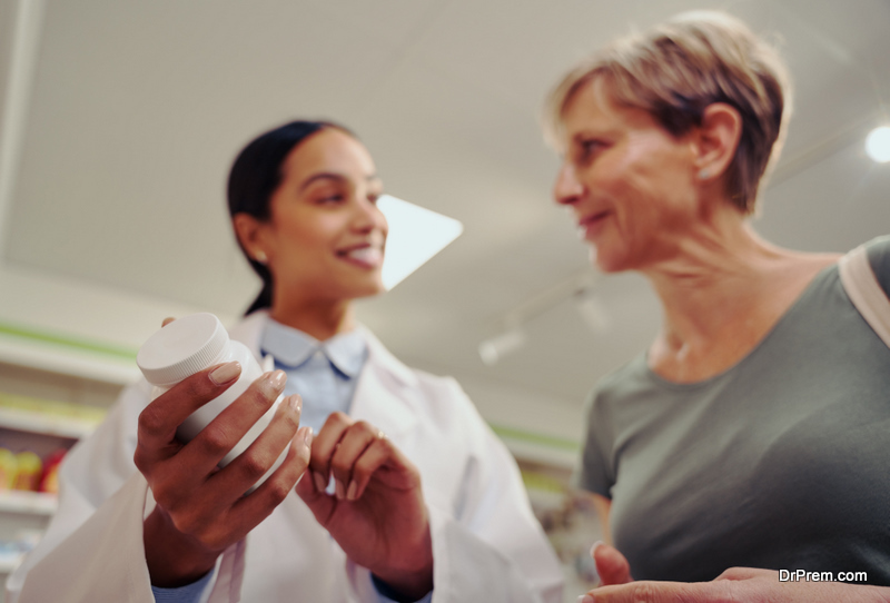 young pharmacist hand holding and checking medicine dosage and ingredients with expiry date standing near shelf in chemist shop with senior woman