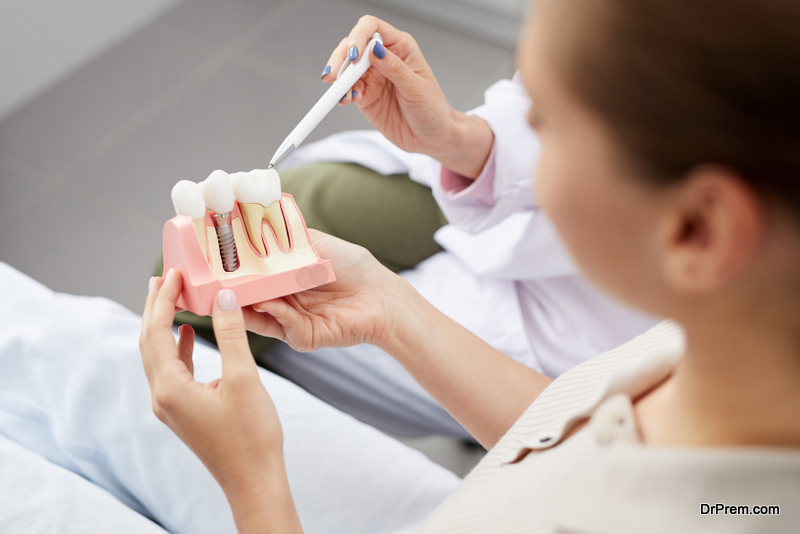 young woman holding tooth model during consultation in dentists office