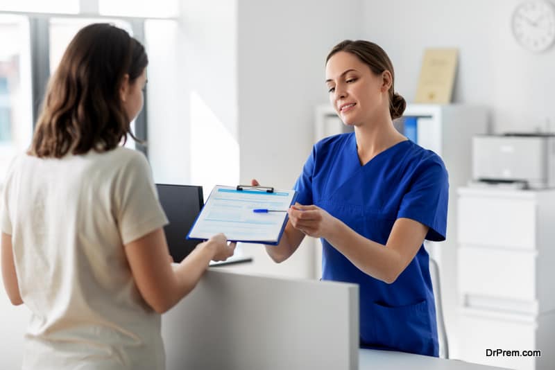 female doctor or nurse with clipboard and patient at hospital