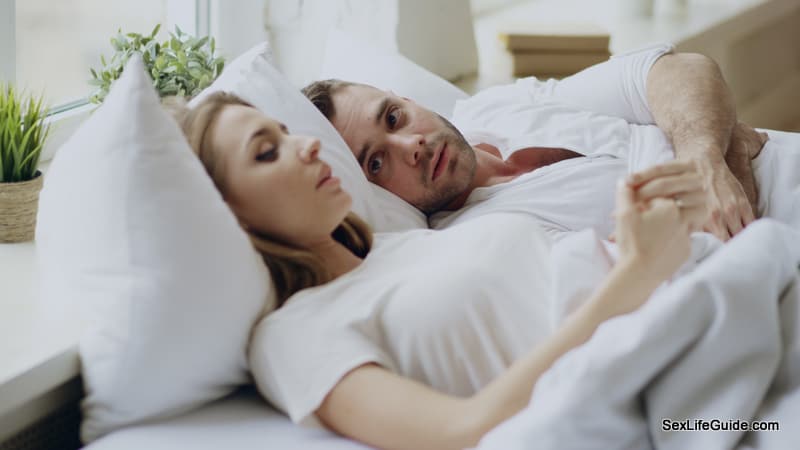 Closeup of couple with problems having emotional conversation while lying in bedroom at home