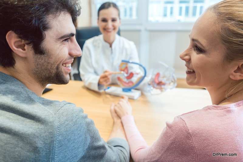 Couple wishing to have children in fertility clinic with doctor looking happy upon good news