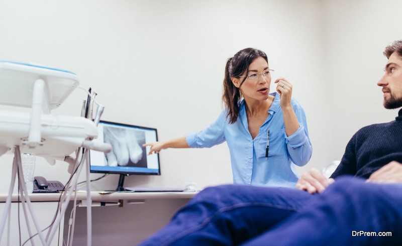 Dentist showing patient the x-ray image of teeth on computer monitor