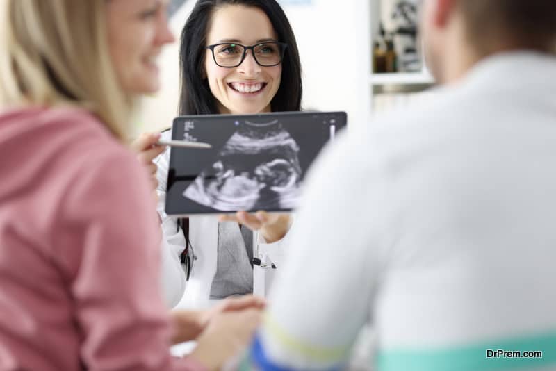 Doctor demonstrates child's ultrasound to couple. Pregnant medical examination concept