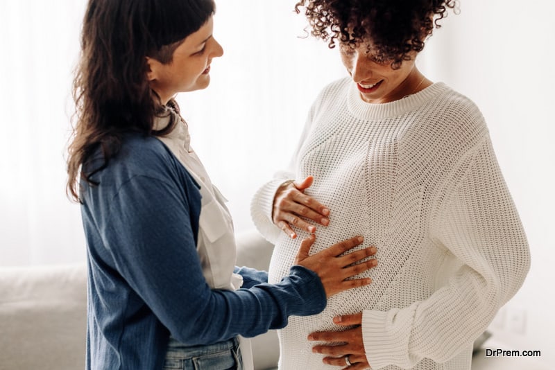 Happy woman touching a surrogate mother's belly bump