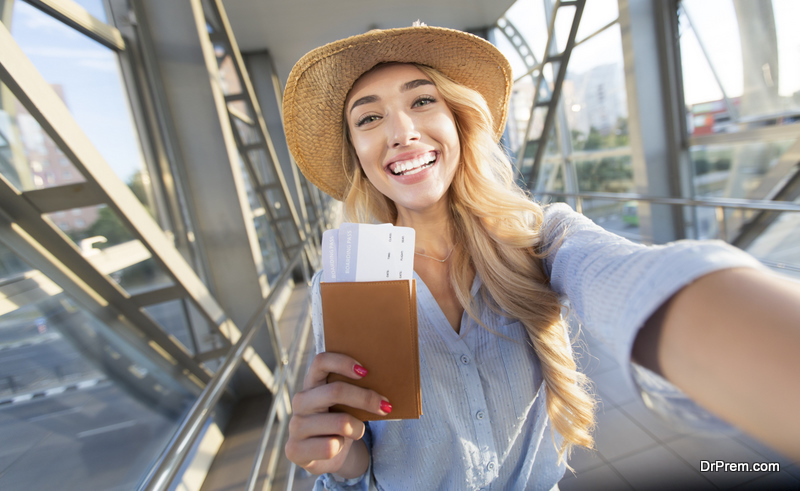 Enjoy traveling. Beautiful woman taking selfie in airport, waiting for boarding