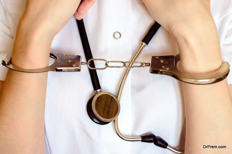 Doctor with stethoscope and hand on handcuffs close up concept of medical malpractice or mistake