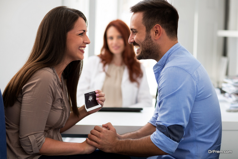 Mother holding ultrasound, holding hands with her husband in a clinic