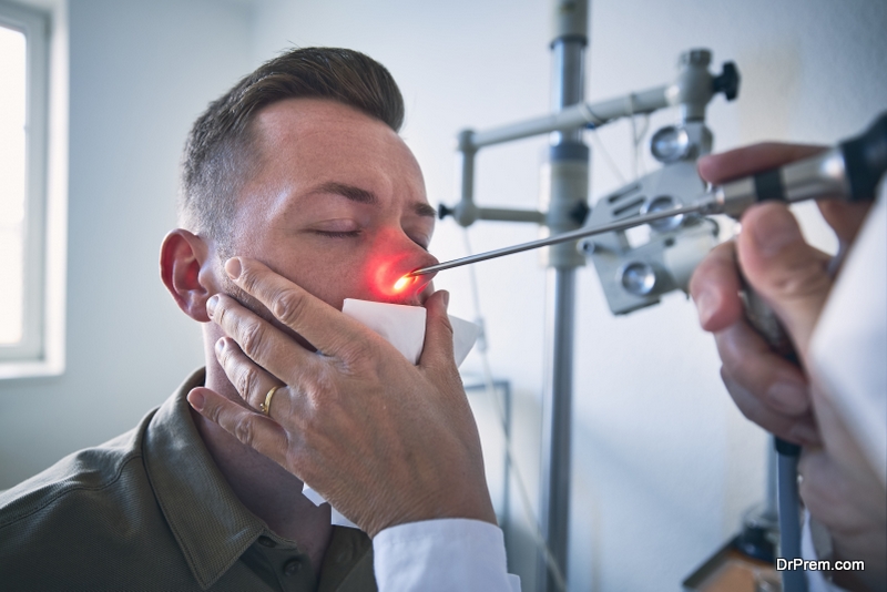 Patient at ENT clinic. Specialist doctor - Otolaryngologist doing nose examination of young man.