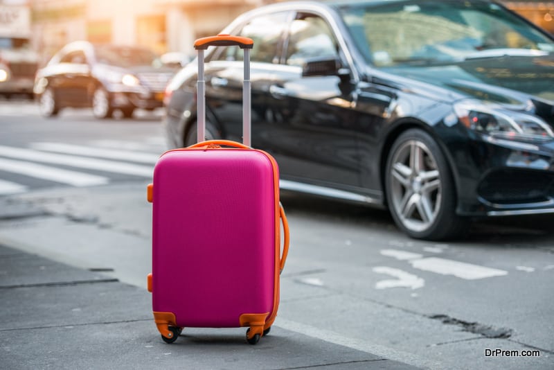 Luggage bag on the city street ready to pick by airport transfer taxy car.