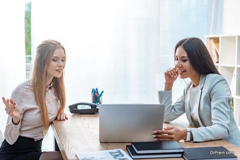 positive travel agent and client talking while looking at laptop screen