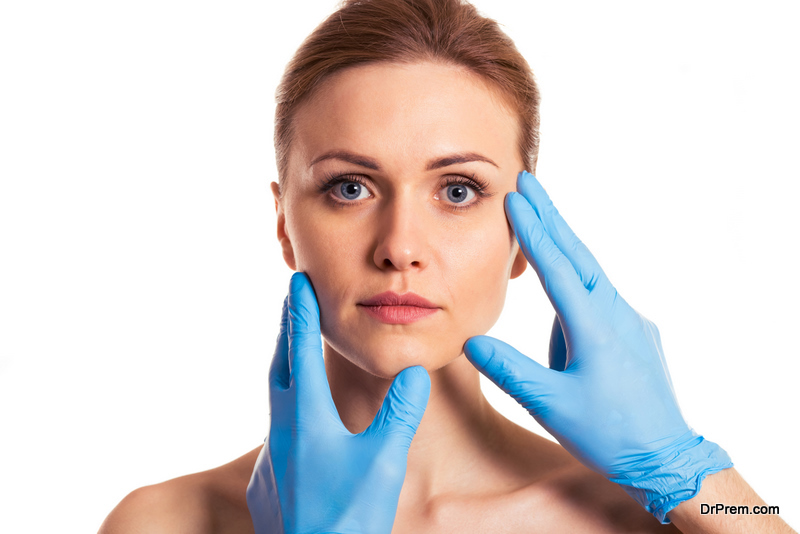 surgeon in blue medical gloves is examining her face