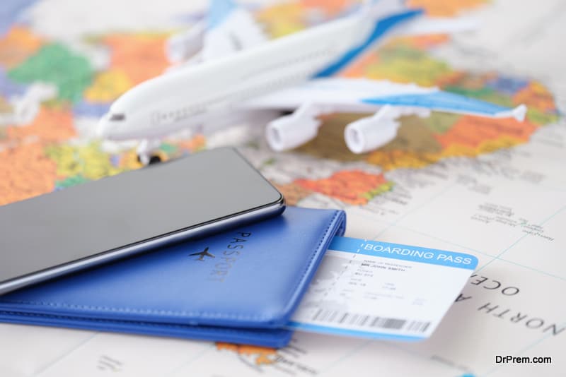 Smartphone with passport and tickets and an airplane lie on geographic map. Searching for profitable offers from air operators through the concept application