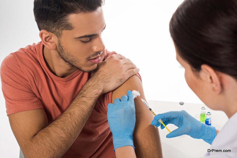 Selective focus of doctor doing injection to handsome patient 