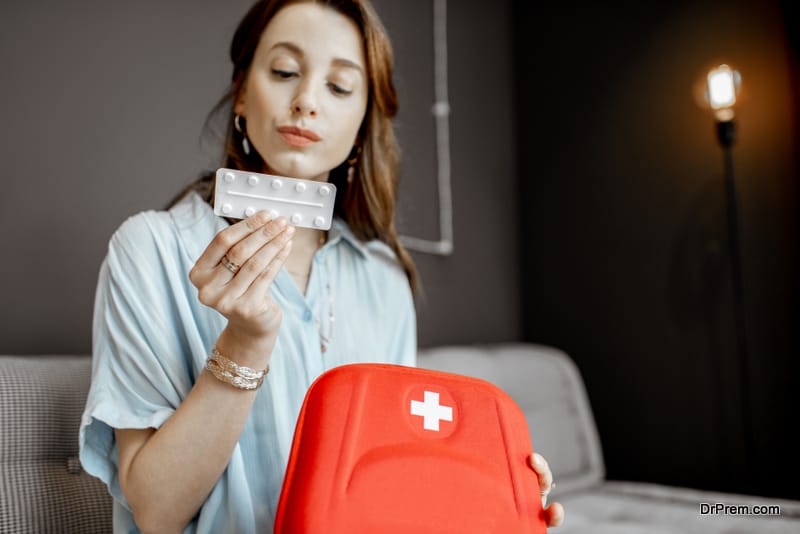 Young woman taking some medicines from the first aid kit