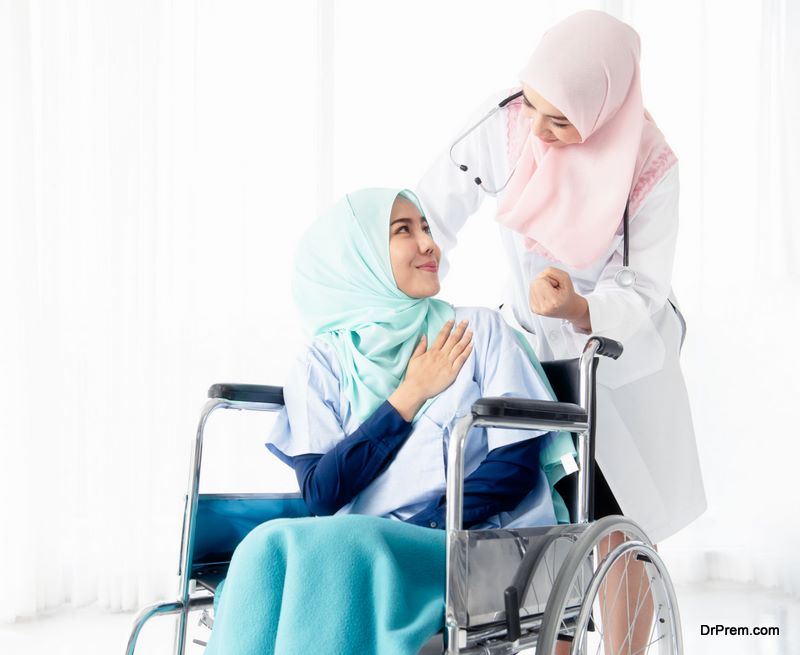 A beautiful Muslim doctor had a stethoscope in his neck, taking the patient to the x-ray examination room by a wheelchair 
