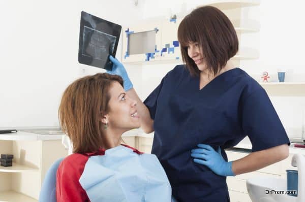 Dentist woman holding x-ray and smiling to the female patient