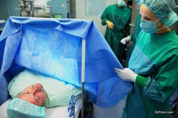 Female operating theatre staff checking on patient on operating table