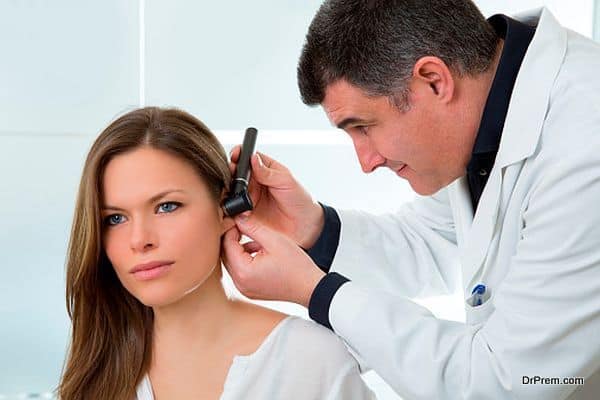 Doctor ENT checking ear with otoscope to woman patient