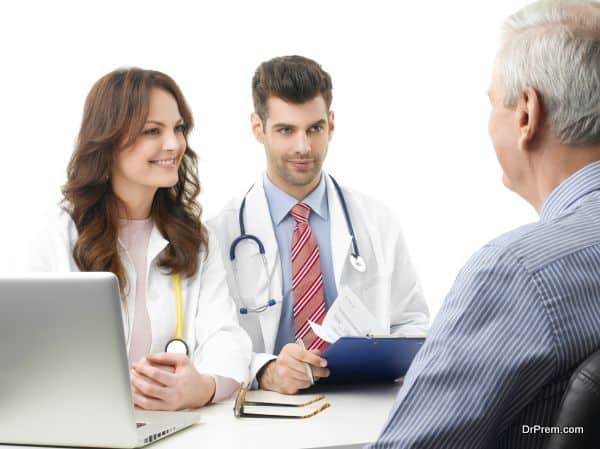 Portrait of young female doctor and male doctor discussing with elderly patient. Isolated on white background.