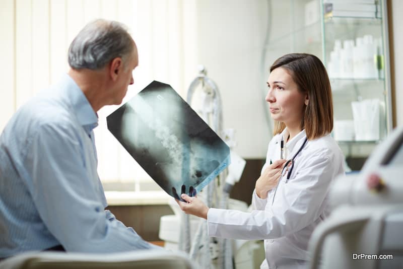 Young radiologist showing x-ray image to her aged patient and giving recommendations about treatment