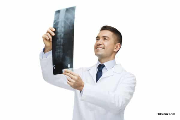 smiling male doctor in white coat looking at x-ray