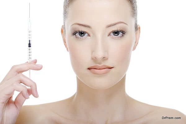 young beautiful woman with syringe in her hand - white background