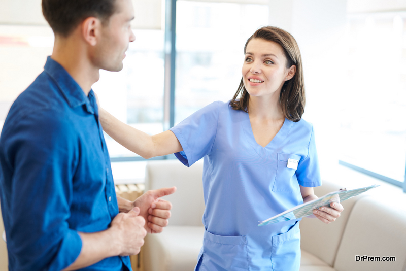 smiling young nurse greeting patient in hall of modern clinic