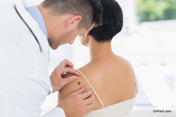 Doctor examining mole on back of woman