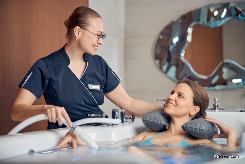 Young female therapist smiling at her patient during the hydrotherapy procedure in a spa salon