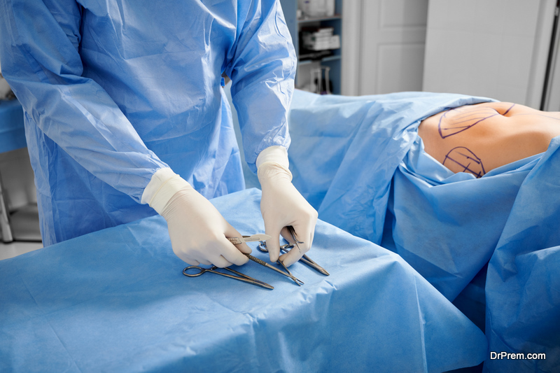 Doctor preparing instruments for liposuction in operating room