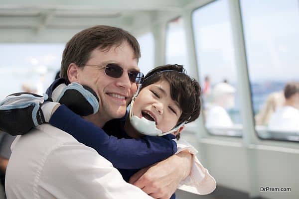 Father hugging disabled son as they ride a ferry boat