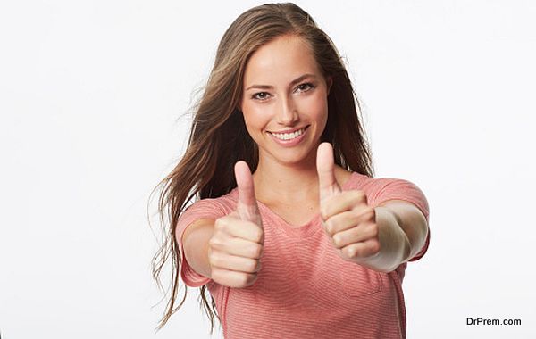 Portrait of young woman with thumbs up in studio