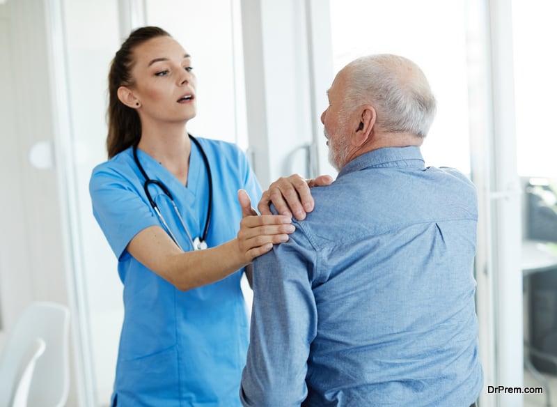 Doctor or nurse caregiver help senior man in pain at home or nursing home