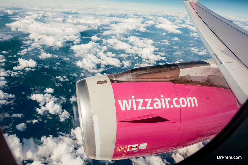 Logo of airline company Wizz Air, on the wing of airplane in flight above the clouds