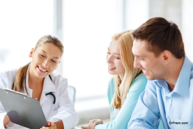  smiling female doctor with clipboard and patients in hospital