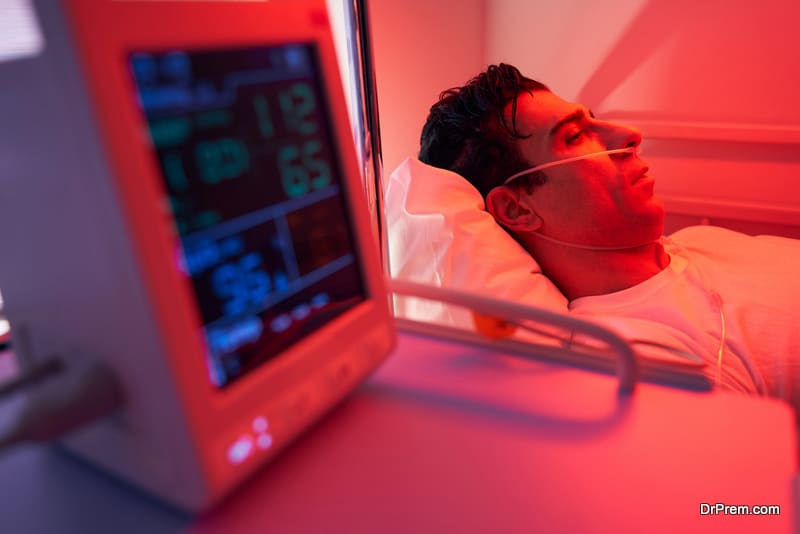 Adult man being treated, liying on bed in the hospital and sleeping, on his face nasal cannula