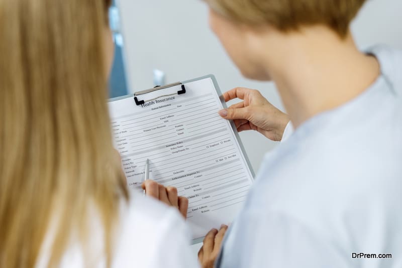 Professional female dentist showing health insurance to patient