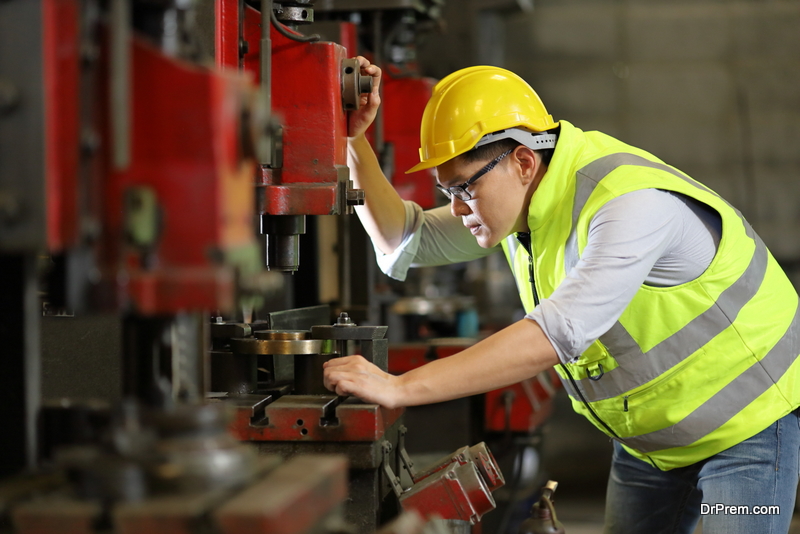 mechanic worker in safety hard hat and reflective cloth is working with lathe machine in the factory 