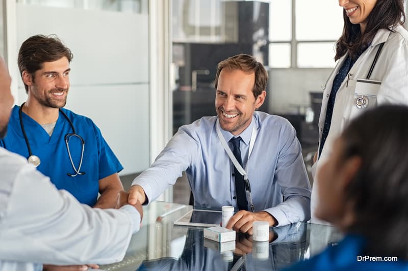 Doctor and representative pharmaceutical shaking hands in medical office