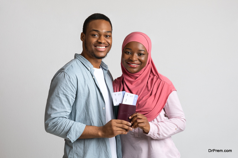 Smiling young muslim couple holding flying tickets and passports, got visa