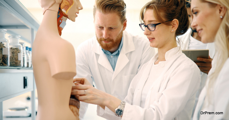 Students of medicine examining anatomical model in classroom 