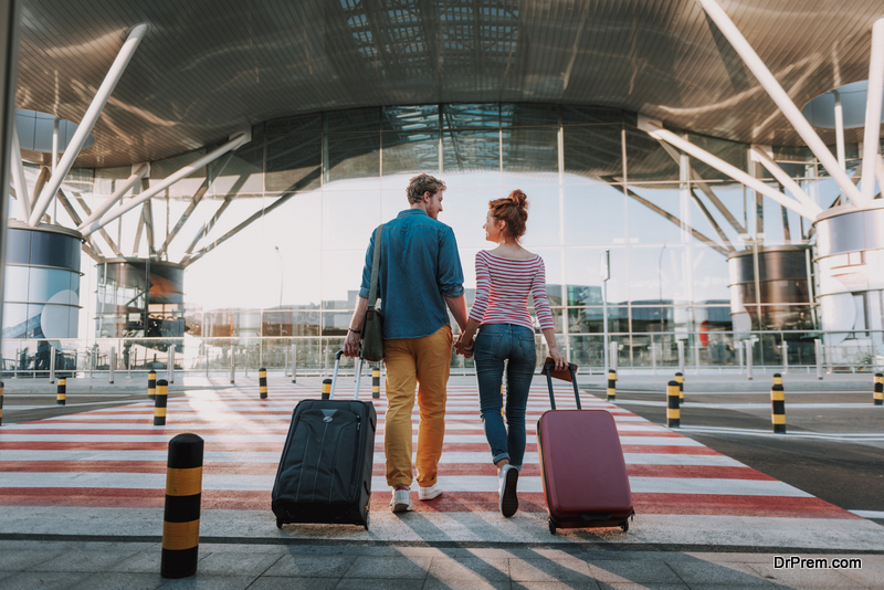 young man and his charming girlfriend walking and carrying their trolley bags