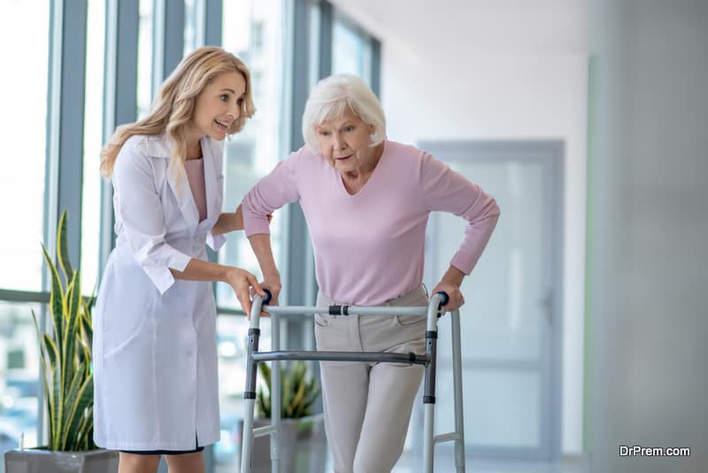 Female doctor in a lab coat encouraging a senior patient with rolling-walker